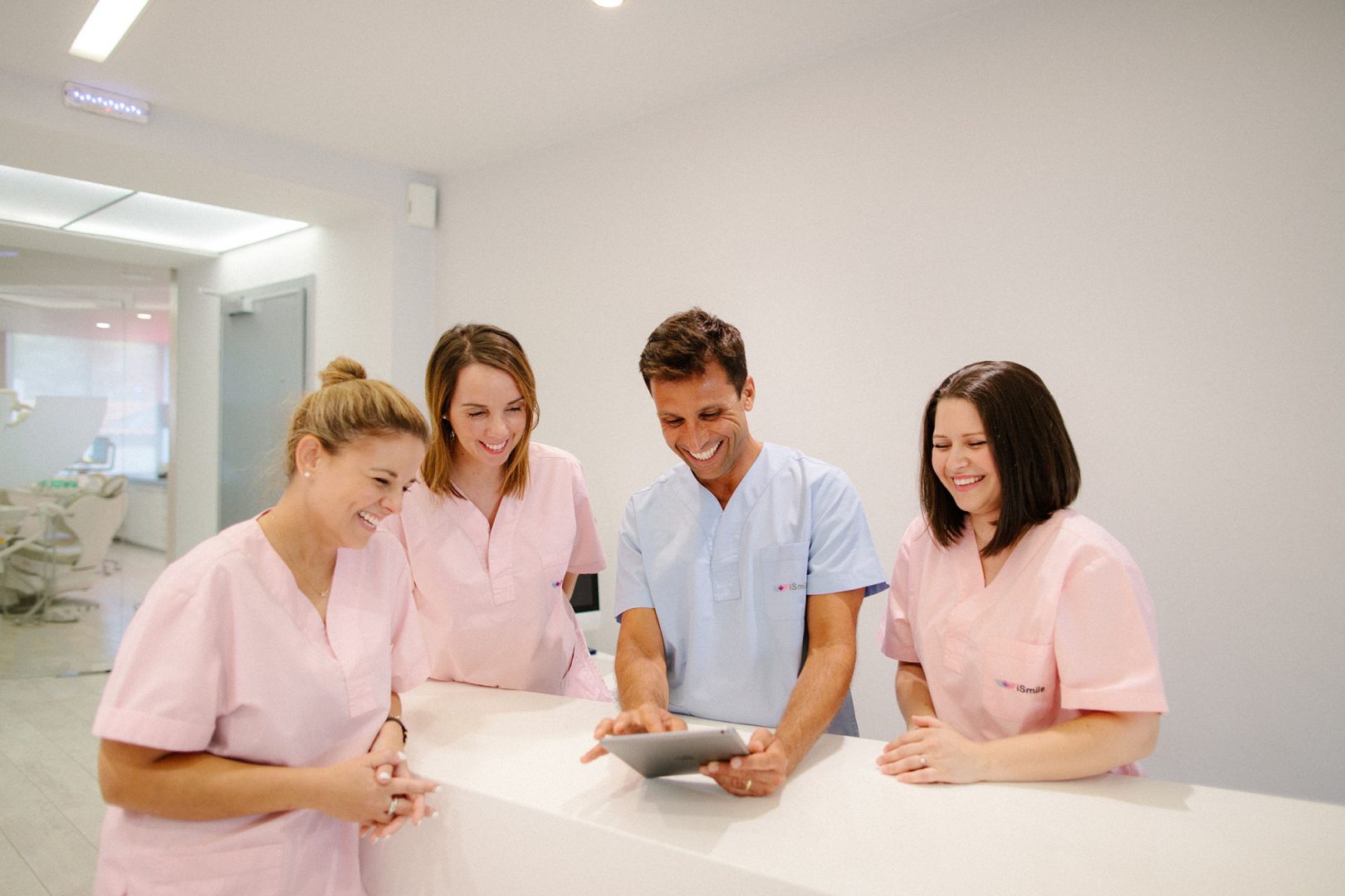team photo, in the clinic's space, all smiling and looking towards a tablet computer